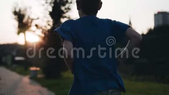 这个男孩在凉爽的日落背景下沿着海滨奔跑令人惊叹的气氛冷静的画面视频的预览图