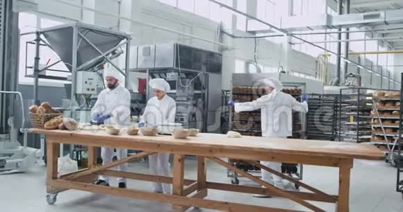 大的商业烘焙行业三个面包师集中制作面团来烘焙面包老人视频的预览图