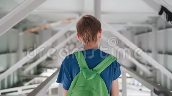 这个男孩走在桥下一条真正的金属走廊上摄像机从后面拍摄回放缓慢视频的预览图