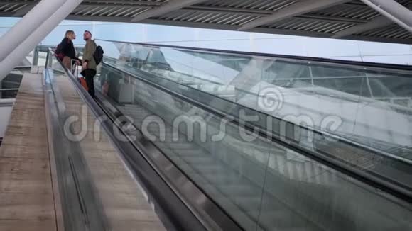 有行李的旅客一对一站在自动扶梯上向下移动视频的预览图