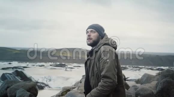 年轻的旅行者站在山顶上看着冰岛的Vatnajokull冰泻湖的冰川视频的预览图