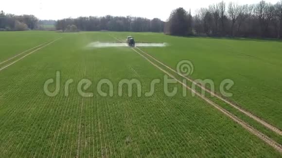 农业拖拉机带喷雾器喷洒春时麦田空中视频的预览图