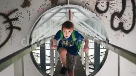 男孩走到桥下爬进一个金属洞里凉爽的金属走廊视频的预览图
