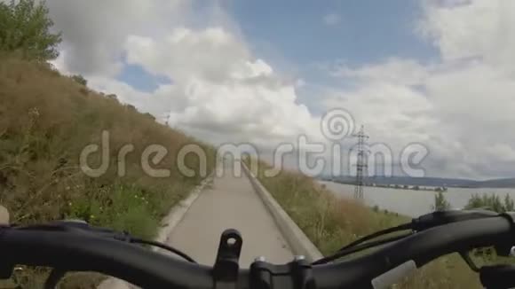 在宽阔的河的高岸上骑自行车视频的预览图