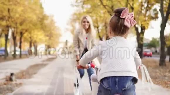 年轻的母亲向她的小女儿解释如何骑自行车视频的预览图