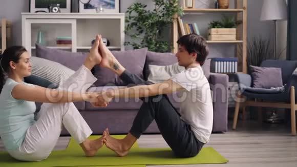 为夫妻一起在公寓锻炼的学生做瑜伽视频的预览图