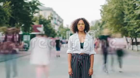 一个漂亮的非裔美国女孩独自站在城市街道上的时间流逝视频的预览图