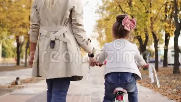 年轻的母亲向她的小女儿解释如何骑自行车视频的预览图