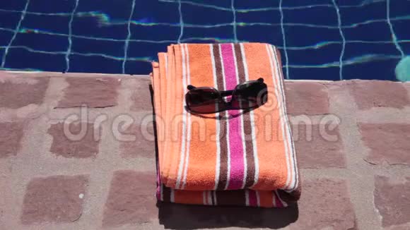 太阳眼镜被风吹落在室外游泳池的毛巾上视频的预览图