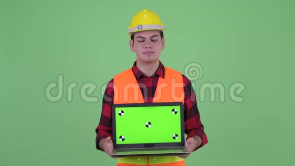 幸福的年轻多民族建筑工人一边思考一边展示笔记本电脑视频的预览图