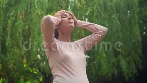 公园里的一个怀孕的女孩在绿柳的背景下平静的女孩抚摸她的头发遮住她的眼睛不受乐趣视频的预览图