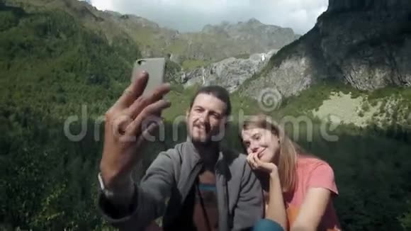 快乐的一对旅人在山上的男人和女人在智能手机上自拍为社交网络拍照视频的预览图