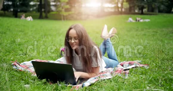 女人躺在草地上拿着笔记本电脑视频的预览图