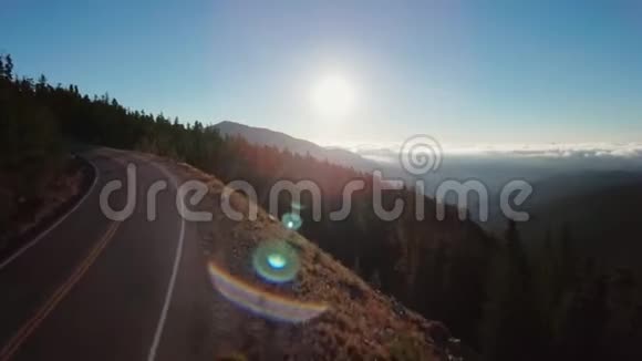 带针叶林的山脉空中拍摄带雾谷的道路和背景中明亮的太阳视频的预览图