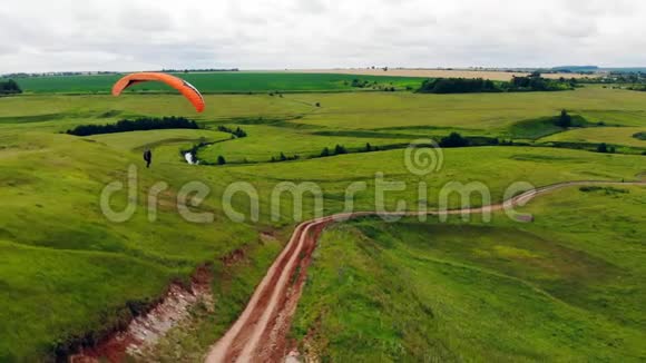 一个拿着滑翔伞的人在空中飞行草甸之上的滑翔伞视频的预览图