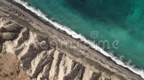 从上到下的鸟瞰绿松石蓝色海浪在原始热带沙滩桑托里尼的岸边破碎视频的预览图