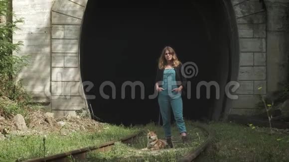 一个女孩站在旧隧道的背景上一个带着狗的女孩站在铁路上视频的预览图