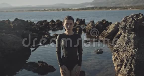 站在海洋附近岩石中的女性性感冲浪者肖像拍摄于12位彩色电影摄影机视频的预览图