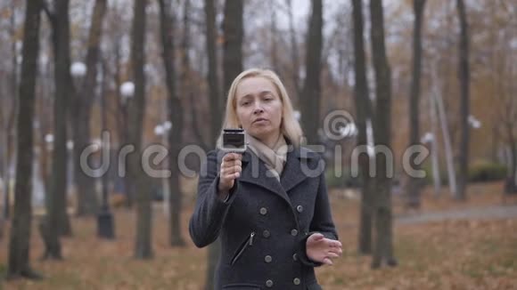 一位女性博客作者在秋天的公园里散步时拍摄了一部溪流动作相机视频的预览图