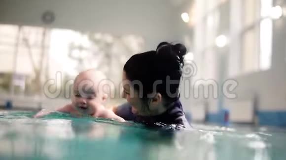 女教练或妈妈教一个小托德勒在水下潜水把他抱在水面上然后一起潜水视频的预览图