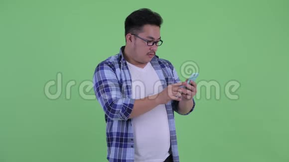 穿着年轻超重的亚洲时髦男人用电话接坏消息视频的预览图