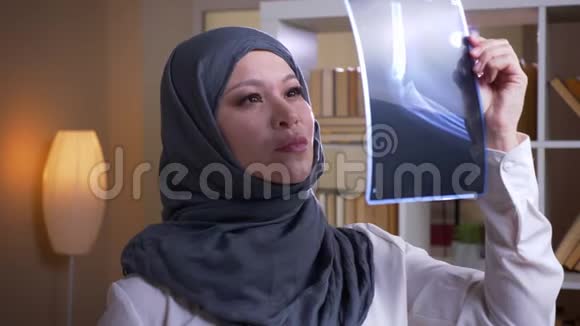 穆斯林成年女医生戴头巾在室内愉快地检查一张x光的特写镜头视频的预览图