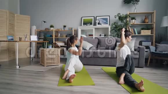 一对男女在公寓里练习瑜伽坐在地板上扭动身体视频的预览图