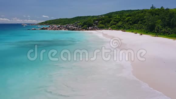 空中盘旋在热带沙滩上的海浪之上白沙浅青色泻湖水和孤独的双体船视频的预览图