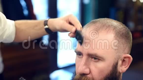 结束发型裁剪好的理发师用修剪好的理发器剪头发给剪在前景上的留胡子的人视频的预览图