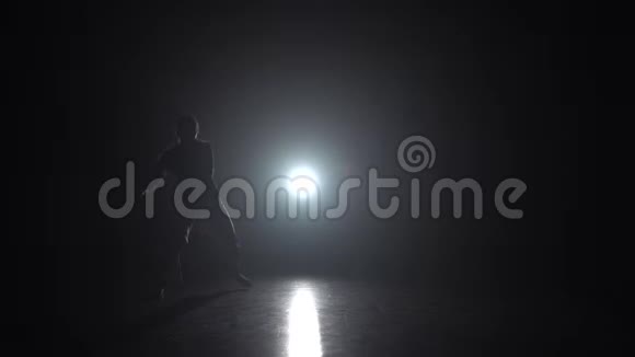 熟练的女士在黑暗中练习卡波伊拉在演播室的聚光灯下慢动作视频的预览图