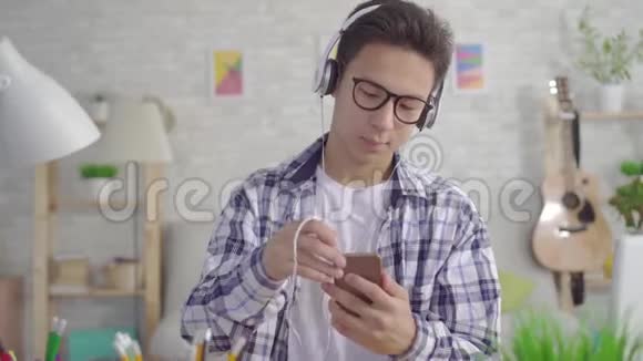一个手持智能手机带耳机听音乐的亚洲年轻人视频的预览图