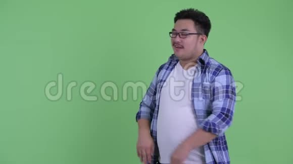 快乐年轻体重超重的亚洲时髦男人一边向后炫耀一边说话视频的预览图