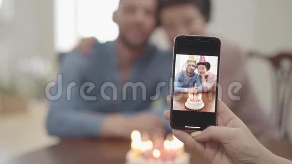 肖像女用手在手机上拍了一张照片照片上的是快乐微笑的成熟女人和成年孙子拥抱在一起两人都在视频的预览图