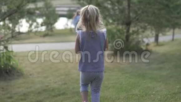 一个小女孩走在绿色的草坪上走向她的父母视频的预览图
