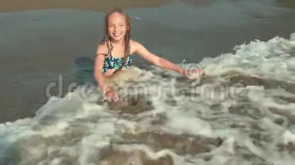 快乐的孩子坐在海水的沙滩上视频的预览图