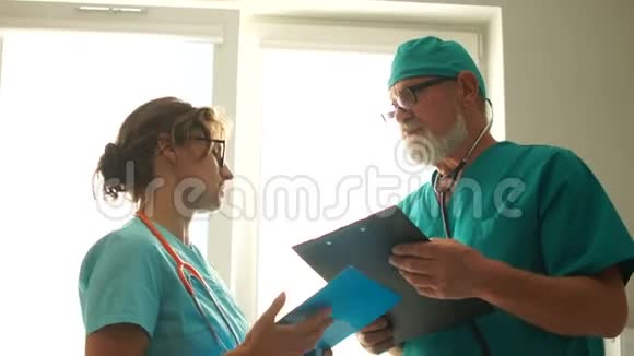两个医生站在医院的窗户前说话男女医生助理讨论视频的预览图
