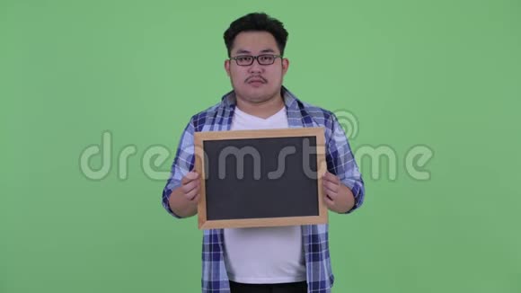 快乐的年轻超重的亚洲潮人一边拿着黑板一边思考视频的预览图