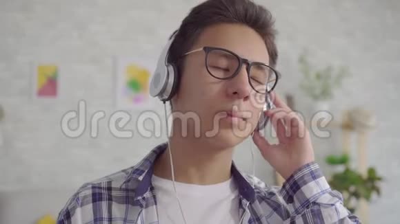 亚洲年轻人用耳机听平静的音乐视频的预览图