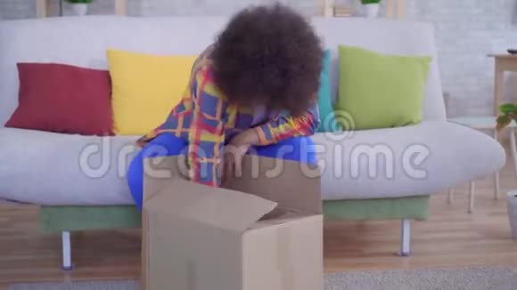 一个非洲发型的非裔美国女人惊讶而沮丧地打开包裹尺寸不对视频的预览图