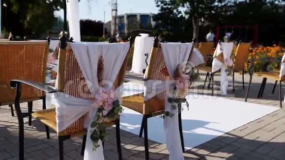在阳光明媚的夏日婚礼地点装饰着鲜花节日花装饰在椅子上玫瑰和视频的预览图
