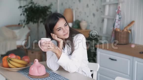 微笑的女人在厨房享受清晨时光喝茶慢动作的肖像视频的预览图