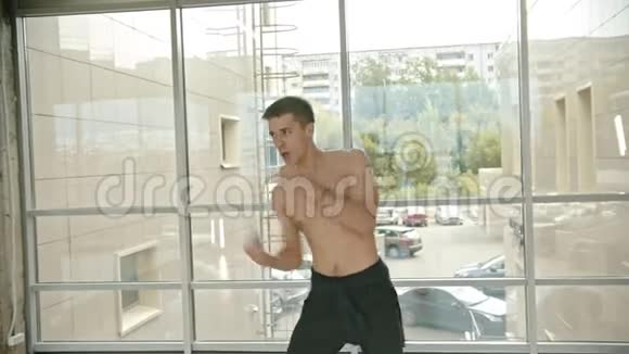 一个半裸运动的拳击手站在窗边和一个影子打比赛视频的预览图