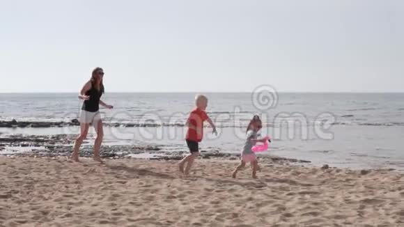 母亲带着孩子在海边的海滩上玩耍视频的预览图