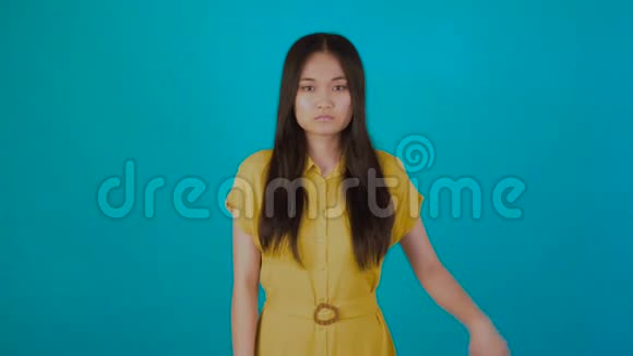 年轻的亚洲少女蓝蓝背景拇指向下标志4K视频的预览图