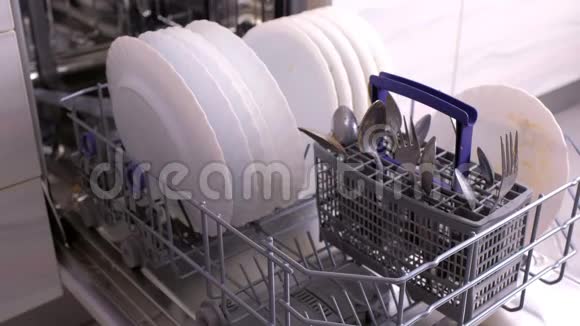 男人手在放白色盘子用脏的白色盘子关闭洗碗机视频的预览图