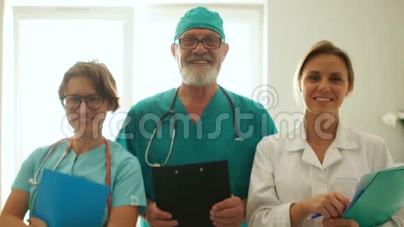 诊所里的三位医生正站在窗口对面微笑医护人员贴身肖像视频的预览图