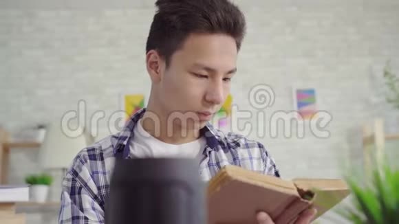 穿着衬衫的亚洲年轻人读一本书用语音助手把书合上视频的预览图