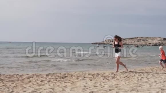 母子正沿着沙滩奔跑儿子和妈妈一起玩赶上大海视频的预览图