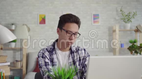 穿着衬衫的年轻人坐在笔记本电脑前咳嗽视频的预览图
