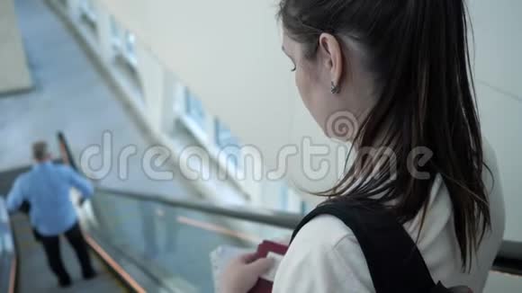 年轻女子拿着文件在机场的自动扶梯下视频的预览图